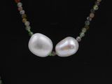 necklace with a white pearl and green beads on a black background