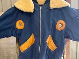blue jacket with yellow patches and a gas mask on a hanger