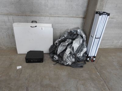 une photo montrant une valise, un trépied et d'autres objets posés sur un sol en béton