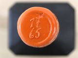a close up of a bottle of orange liquid on a table