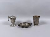 deux tasses en argent et une tasse en argent posées sur une surface blanche