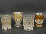 several different colored glass cups and glasses on a black surface