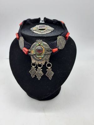 Le collier est en métal et est entouré d'un cordon rouge.