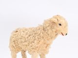 a small toy sheep that is standing on a white surface