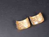 two gold cuff bracelets on a black surface