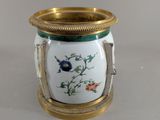 un vase blanc orné d'un liseré doré et d'une fleur bleue