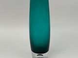 un vase en verre vert posé sur une surface blanche