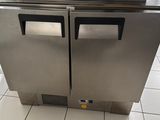 congélateur à double porte en acier inoxydable posé sur un sol carrelé dans une cuisine professionnelle