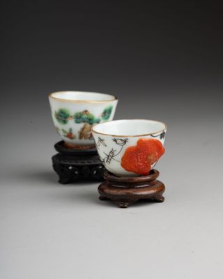 deux petites tasses ornées de motifs, posées sur un support en bois