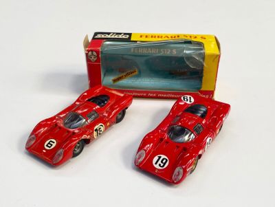 deux petites voitures rouges posées l’une à côté de l’autre sur une surface blanche