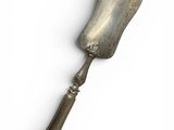 an old silver spoon with a handle on a white surface