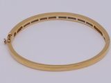 a close up of a gold bang bracelet on a white surface