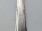 a silver spoon with a handle on a white surface