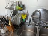 un évier de cuisine avec de nombreux ustensiles posés sur le plan de travail