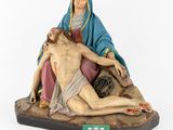 a statue of jesus on the cross with a woman laying on the ground