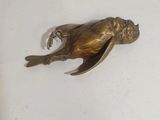 a bronze frog that is sitting on a white surface