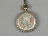 a silver pocket watch with a floral design on it
