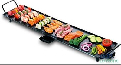 une image représentant un long barbecue noir sur lequel sont disposés divers types d'aliments