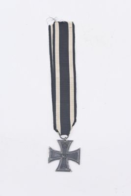 une médaille représentant une croix de fer, accompagnée d'un ruban noir et blanc, sur fond blanc