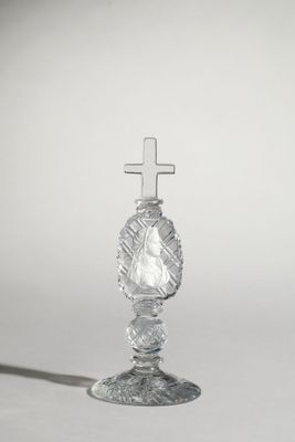 une image représentant un bougeoir en verre surmonté d'une croix