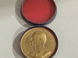 a close up of a coin with a red tin in it