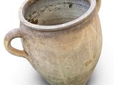 a clay pot with a handle on a white surface