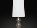 a clear glass lamp with a white shade on a black background