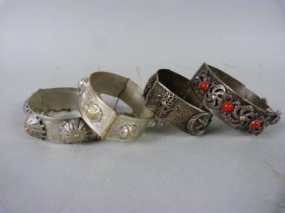 trois bracelets en argent ornés de pierres rouges, posés sur une surface blanche