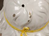 a white ceramic figurine of a dog with a yellow ribbon around its neck