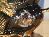 a black and gold vase with a bird design on it