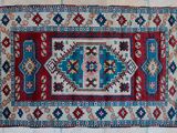 a red and blue rug on a tiled floor next to a brick wall