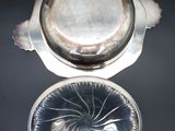 an antique silver plate with a lid on a black surface
