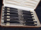 six black and white pens in a case on a black surface
