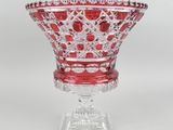une image représentant un bol en verre rouge posé sur un socle transparent
