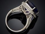 a close up of a blue sapphire and diamond ring on a black surface