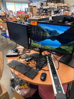 a desk with two monitors and a keyboard on it