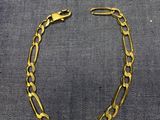 un bracelet à chaîne en or avec un fermoir, sur fond gris