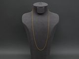 a mannequin with a gold chain on a black background