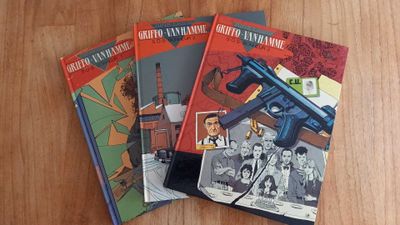 three books on a wooden table with a gun on top of them