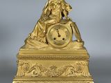 l'image d'une horloge en or sur laquelle est assise une femme