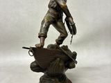 bronze statue of a man on a boat on a wooden base
