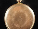an antique gold pocket watch on a black surface with a black background