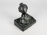 statue of a dog sitting on a box on a white surface