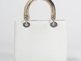 a white handbag with gold handles on a white background