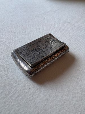 un petit étui à cigarettes en argent posé sur une table