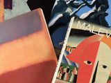 trois livres posés sur une surface blanche, avec une peinture représentant un homme et une femme