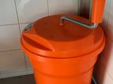 an orange bucket with a handle sitting on the floor