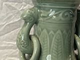 a green vase with a handle and a handle on it