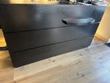 a black dresser sitting on top of a hard wood floor