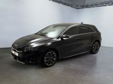 La voiture noire est garée dans une grande pièce aux murs blancs.